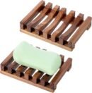 Two natural teak wooden soap dishes with slatted drainage design. One holds a light green soap bar. Compact size, water-resistant wood for bathroom, shower or sink use.